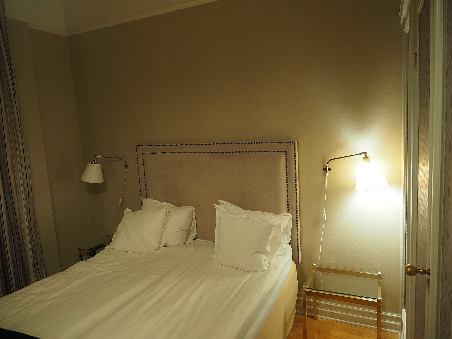 Neatly made bed with white linens in a warmly lit hotel room