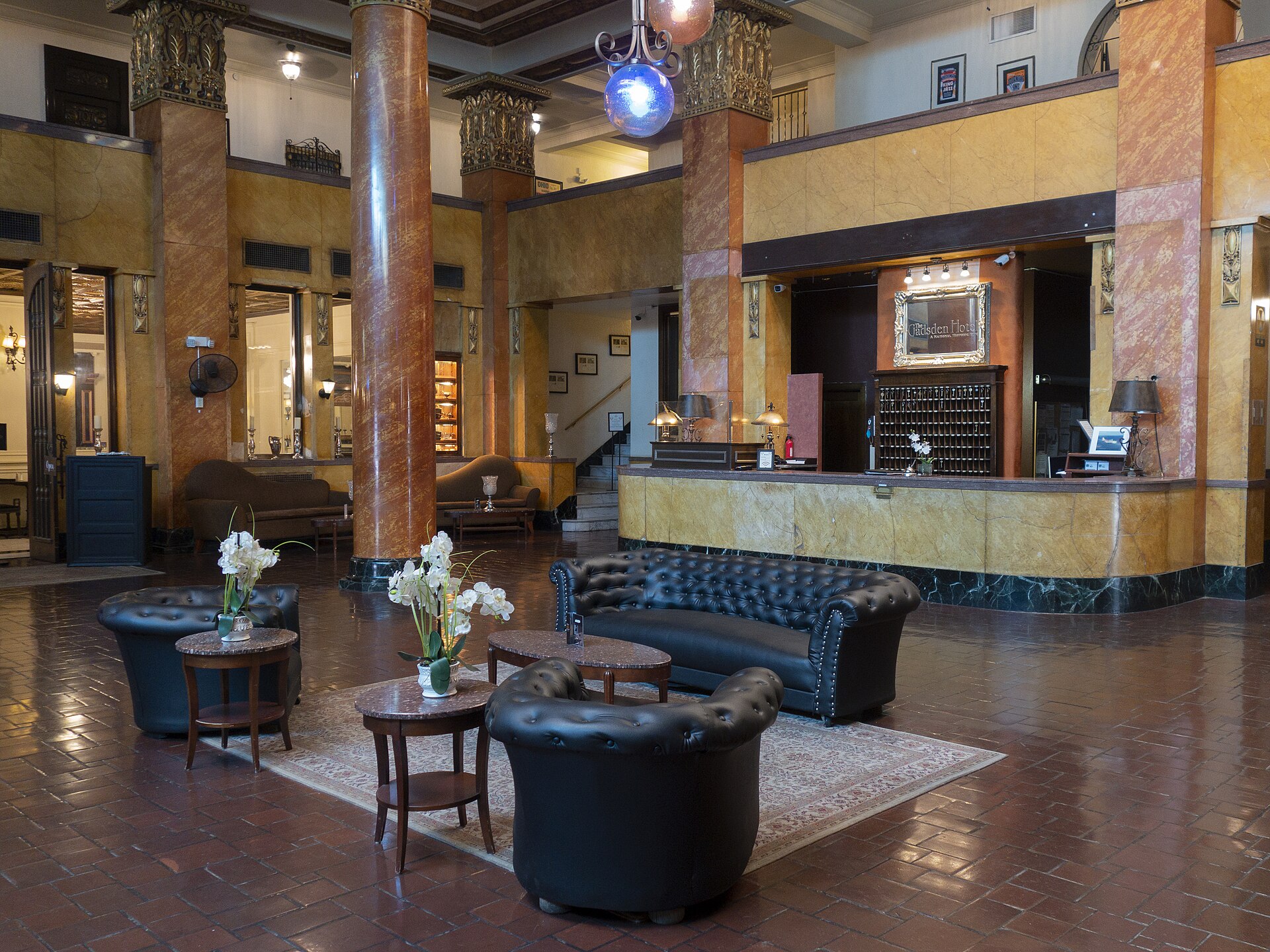 Lobby of a historic hotel with ornate columns, leather seating and a reception desk