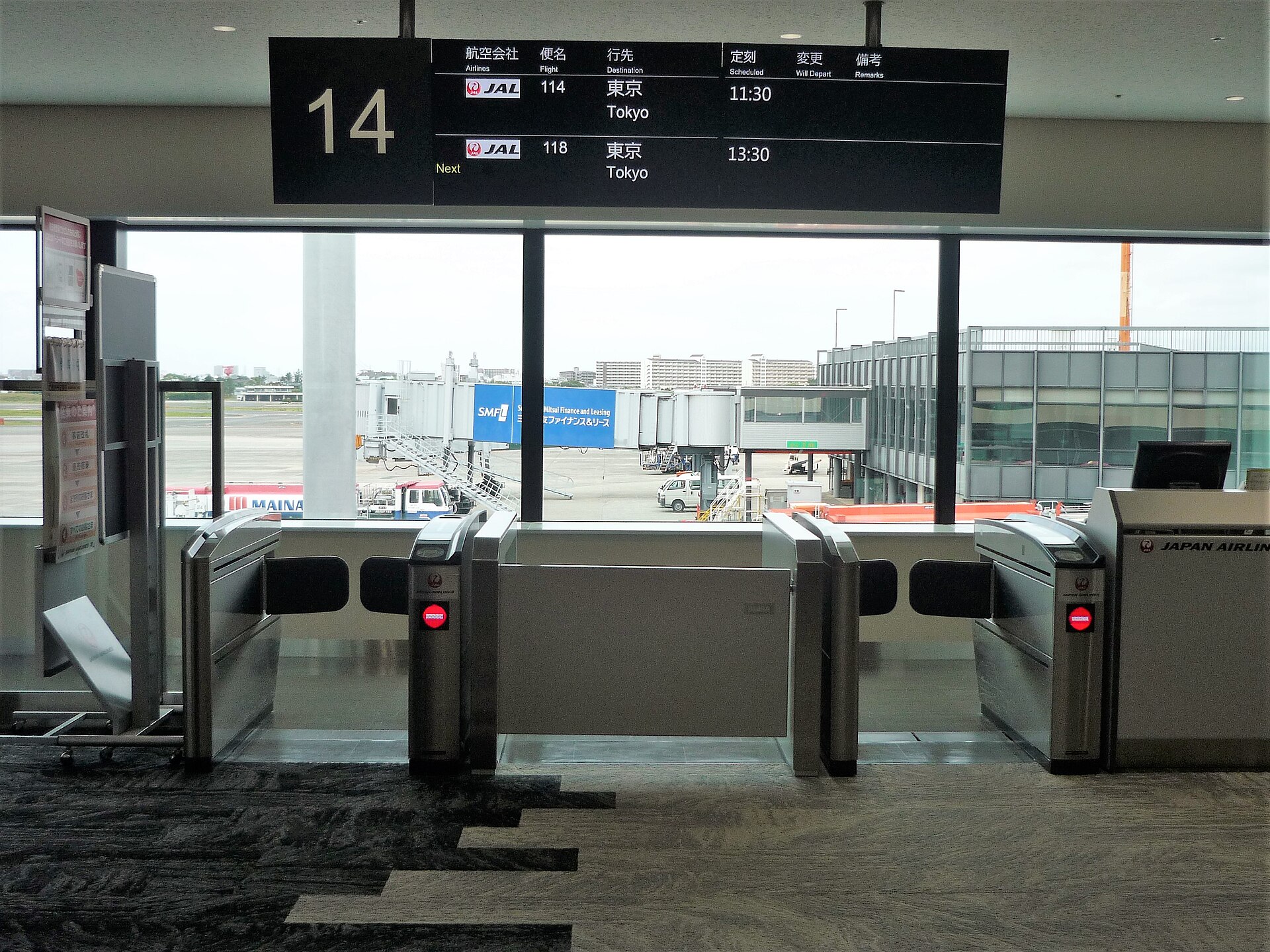 Airport boarding gate with waiting-area seats and flight information displays