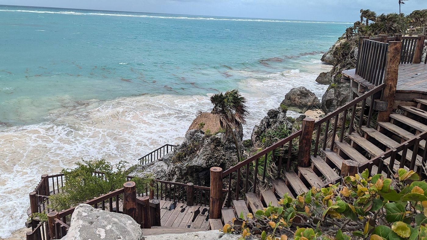 Stone steps leading down to turquoise Caribbean water at the Tulum Maya site